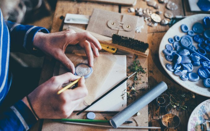 Close-up of hands crafting jewelry from clay at a work table